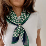Person wearing a green and white checkered scarf on a plain background
