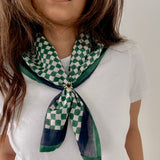 Person wearing a green and white checkered scarf on a plain background