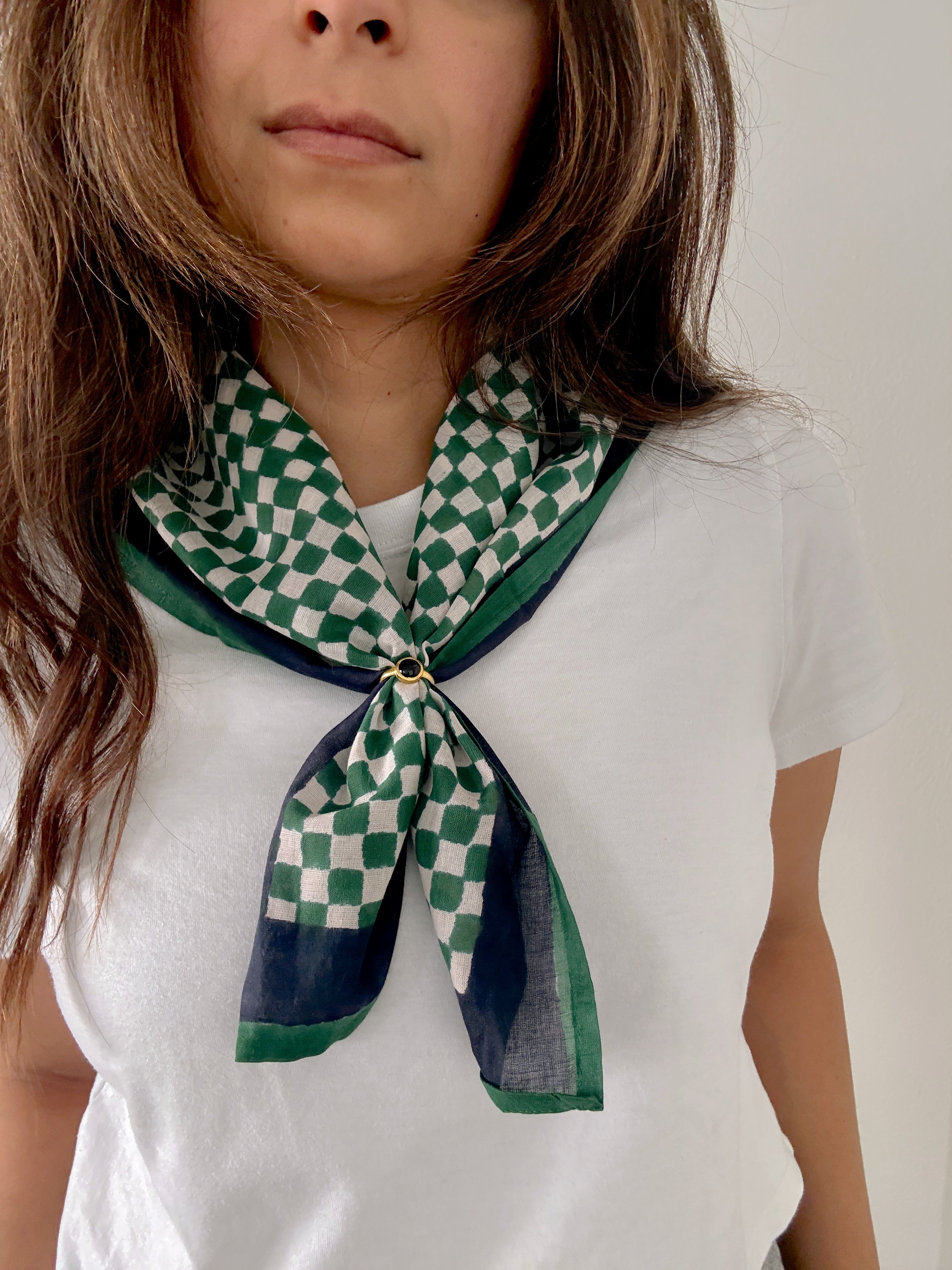 Person wearing a green and white checkered scarf on a plain background