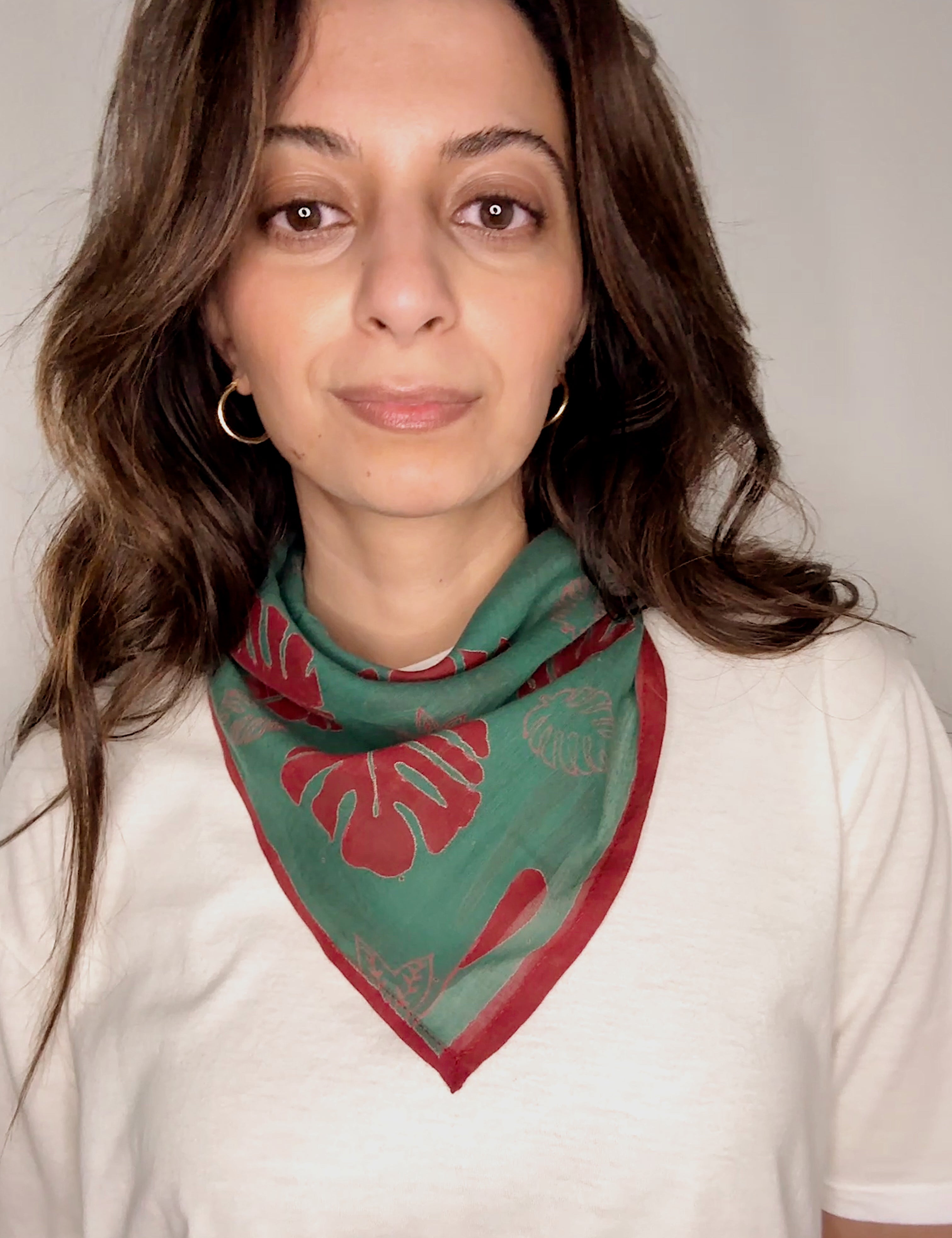 Woman wearing block printed red and green Monstera bandana around the neck