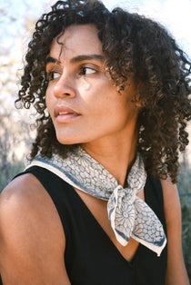 Woman wearing block print Mosaic bandana tied around neck against a black sleeveless dress.