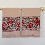 Block printed Rosebud hand towels, hanging on a golden rod. Towels have a rose border print.