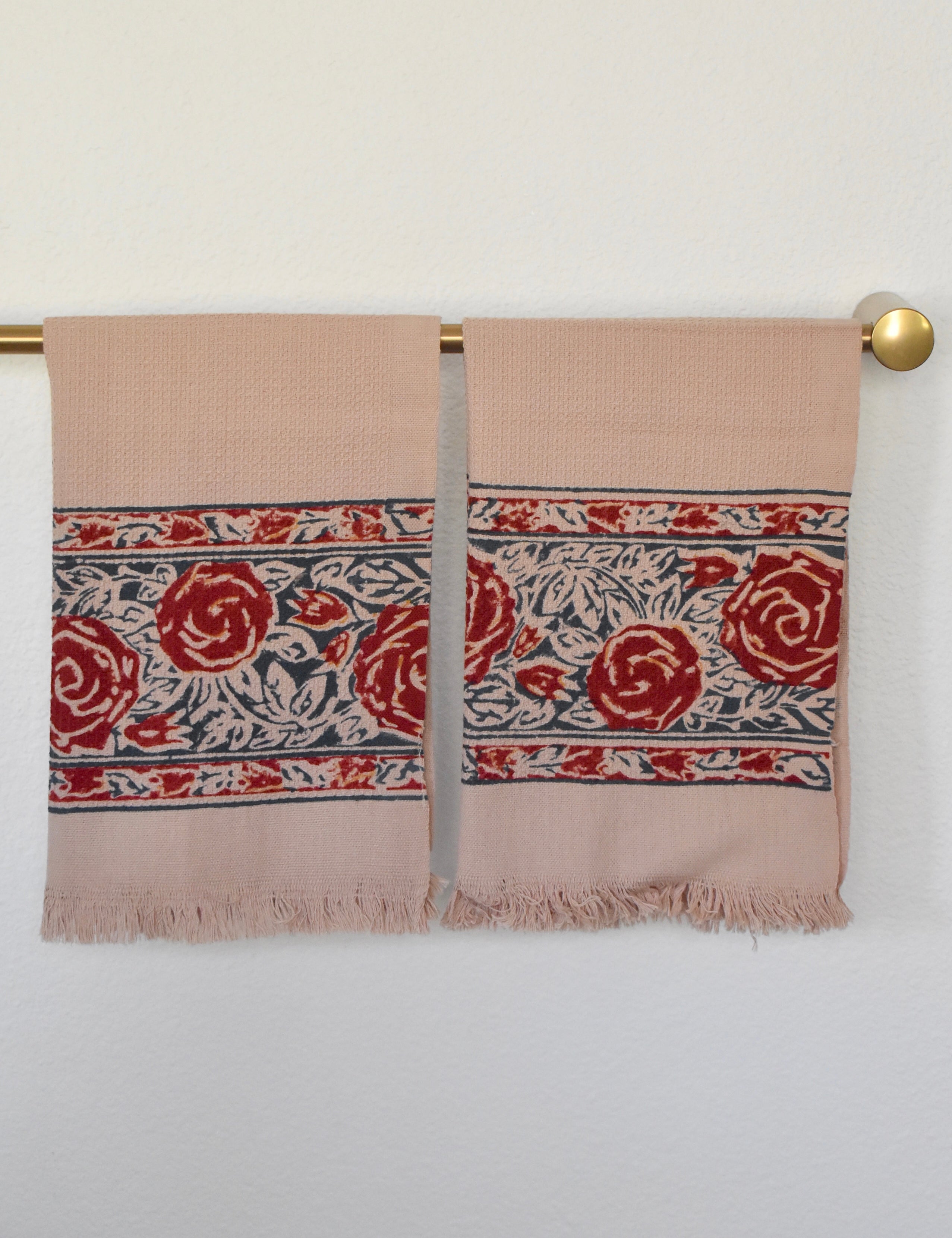 Block printed Rosebud hand towels, hanging on a golden rod. Towels have a rose border print.