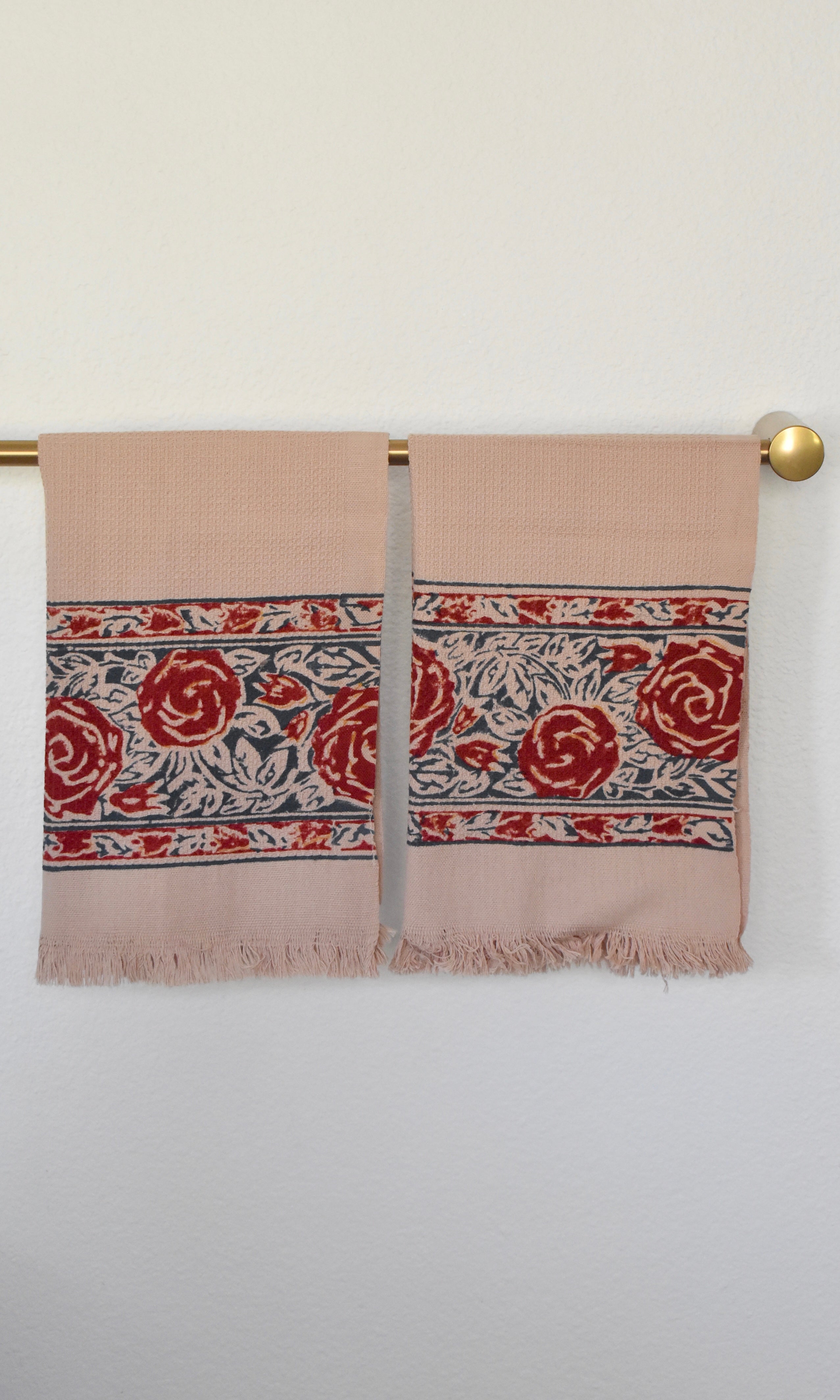 Block printed Rosebud hand towels, hanging on a golden rod. Towels have a rose border print.