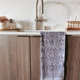Kitchen sink area with a purple floral towel hanging on a wooden cabinet.