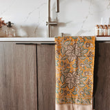 Decorative floral towel hanging on a kitchen cabinet with a marble backsplash.