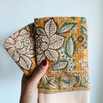 Hand holding folded towels with floral pattern against a plain background