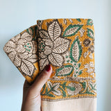 Hand holding folded towels with floral pattern against a plain background