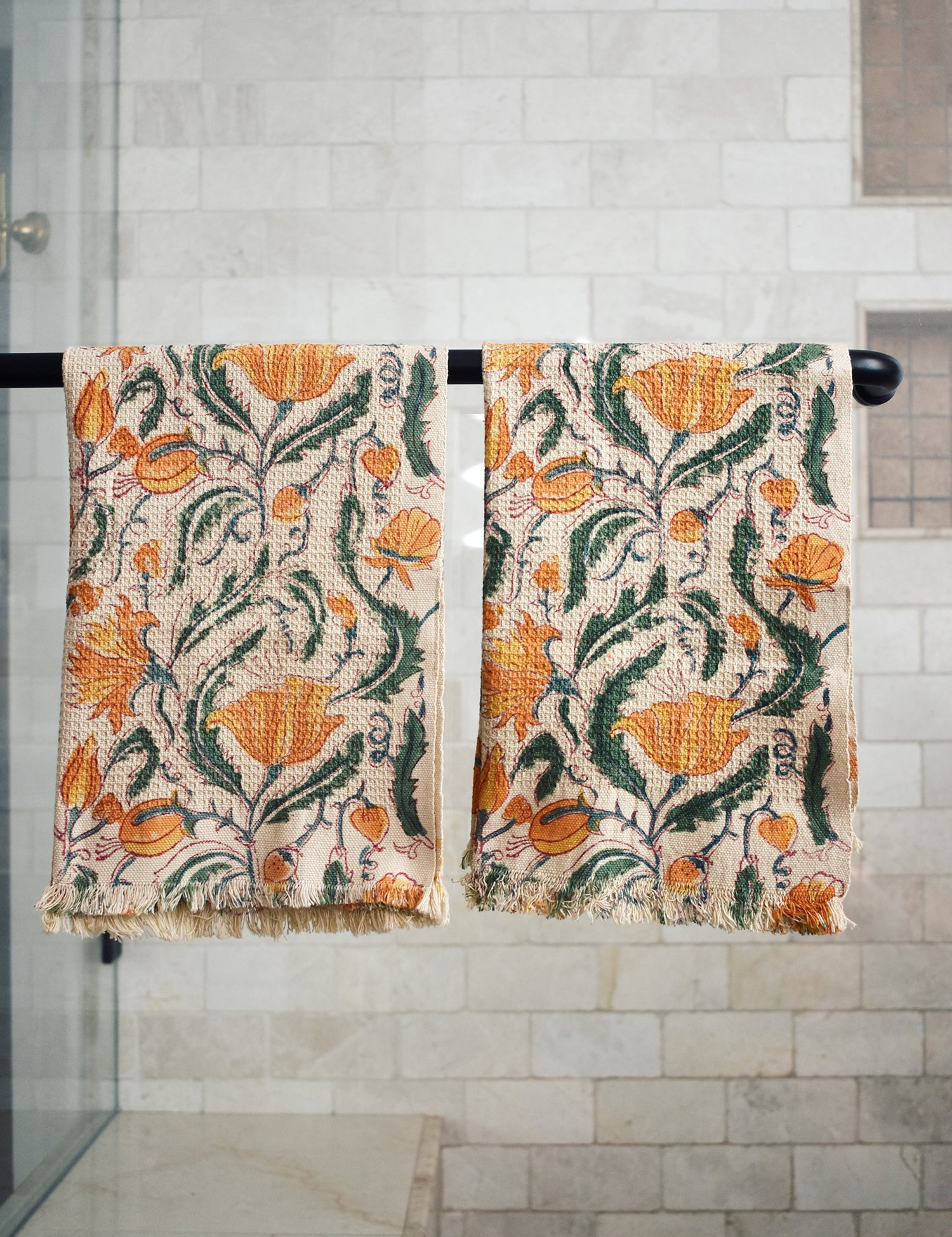 Block printed Tuscan hand towels hanging on a black rod outside a shower
