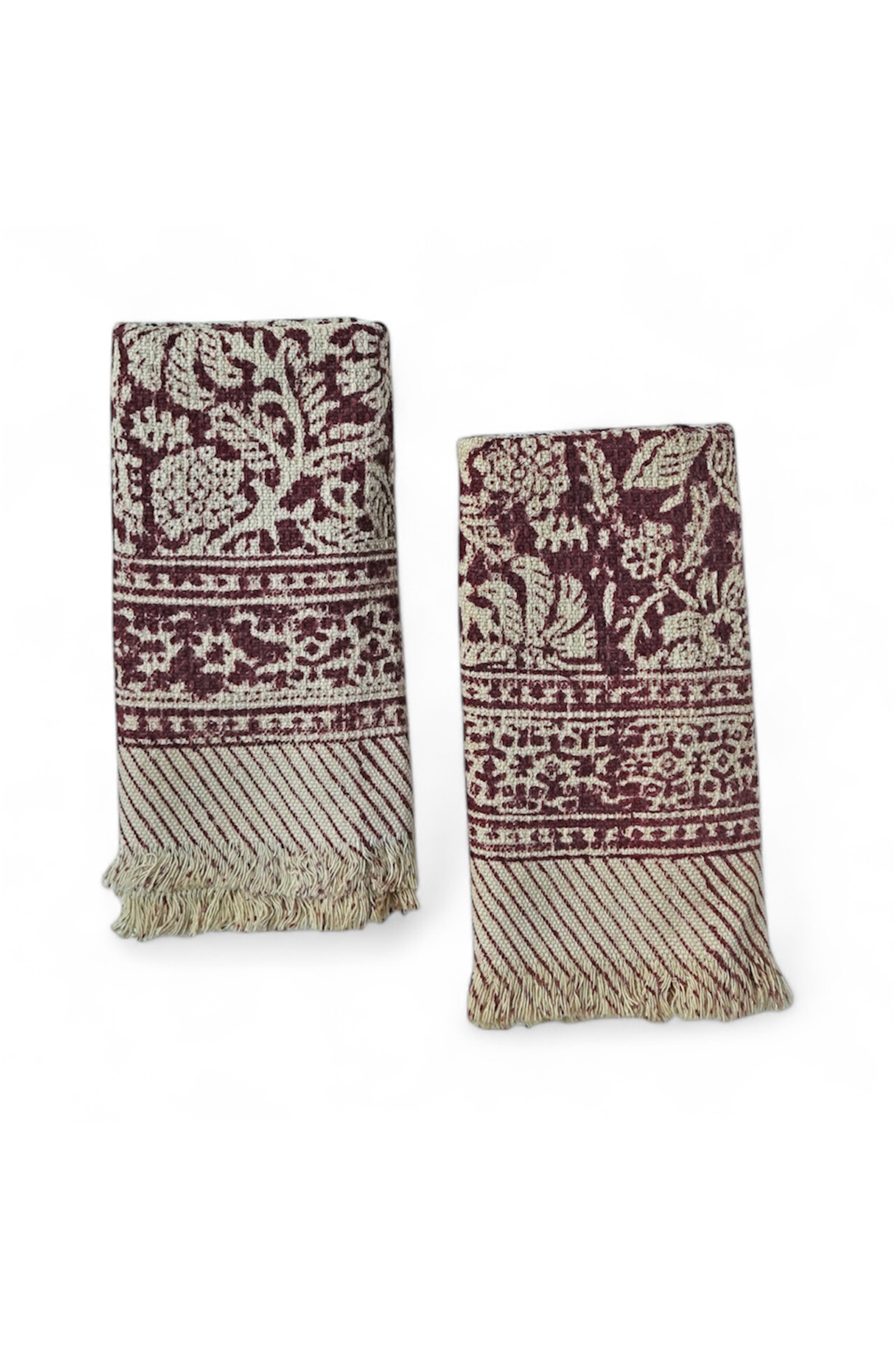 Two patterned hand towels with red floral pattern and fringes on a white background