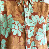 Close-up of a floral shirt with orange and green flowers.