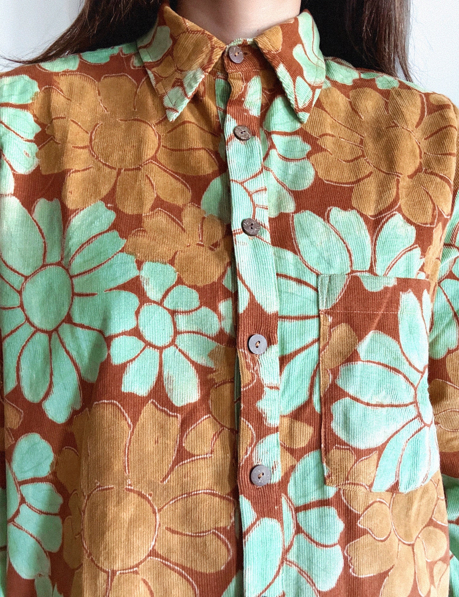 Close-up of a floral shirt with orange and green flowers.