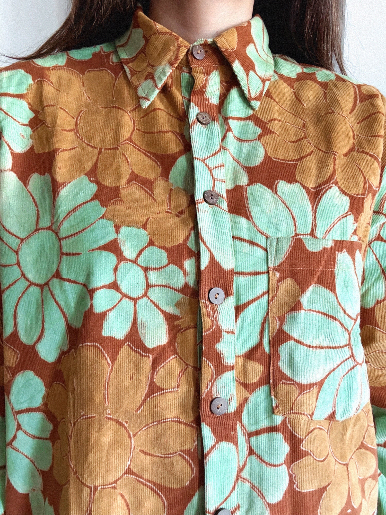 Close-up of a floral shirt with orange and green flowers.