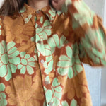 Person wearing a floral shirt with orange and green flowers.