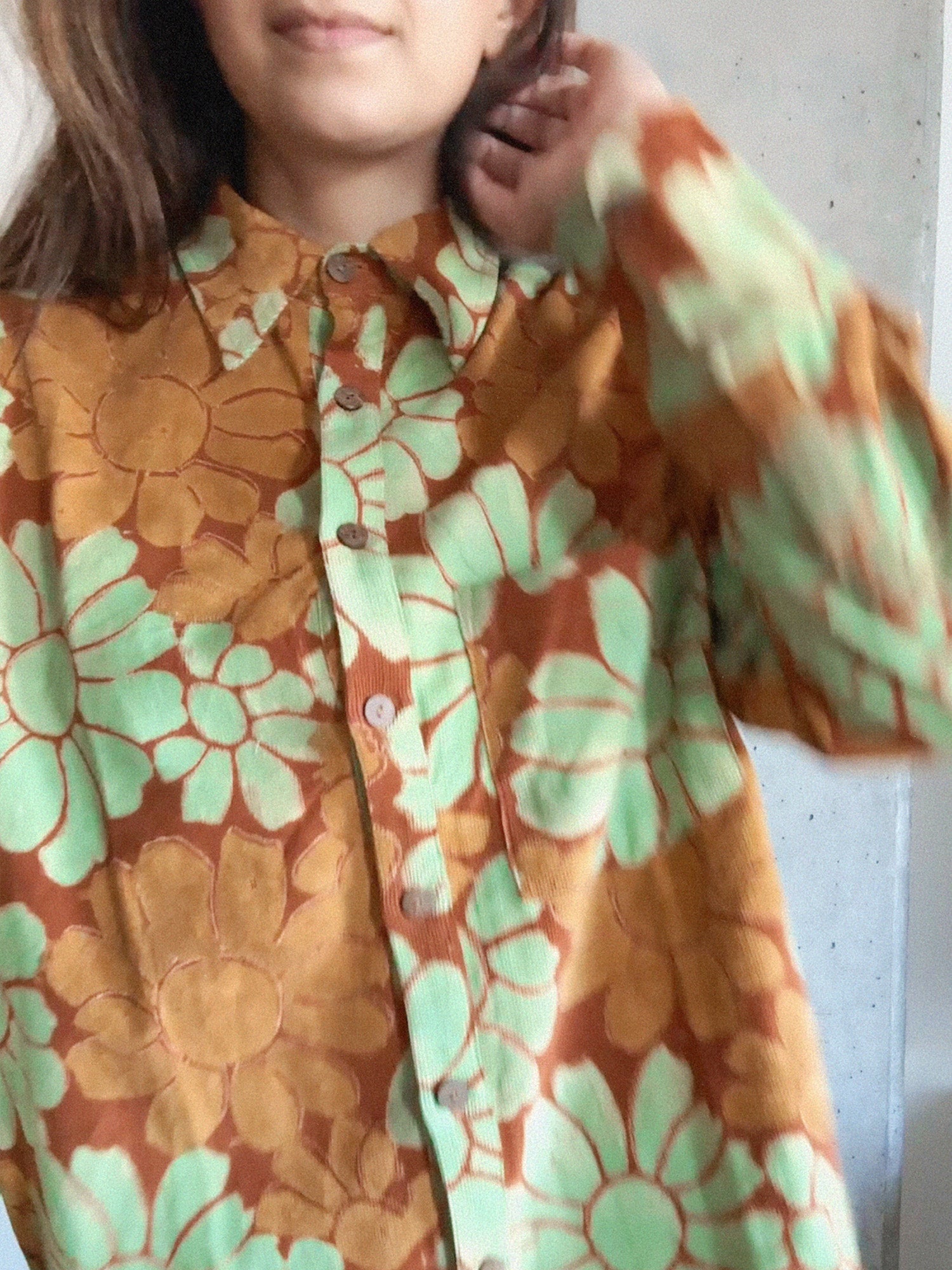 Person wearing a floral shirt with orange and green flowers.