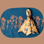 Marigold placemat with floral print, back design, styled with Marigold napkin on top, tied into a napkin ring. 