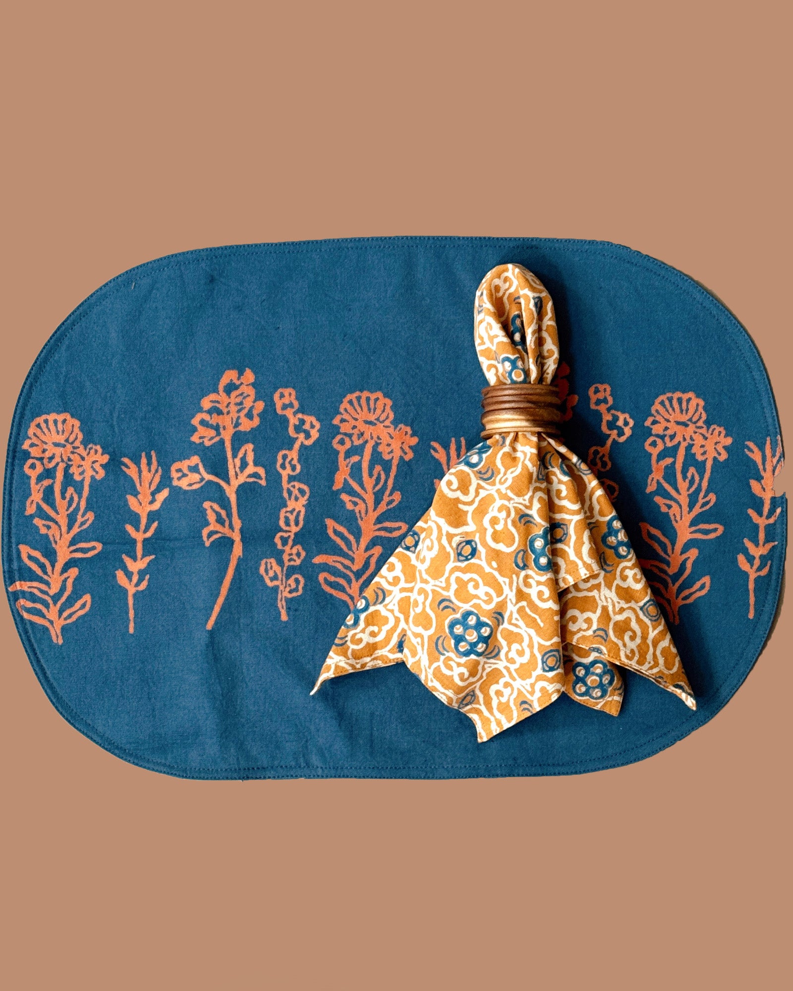 Marigold placemat with floral print, back design, styled with Marigold napkin on top, tied into a napkin ring. 