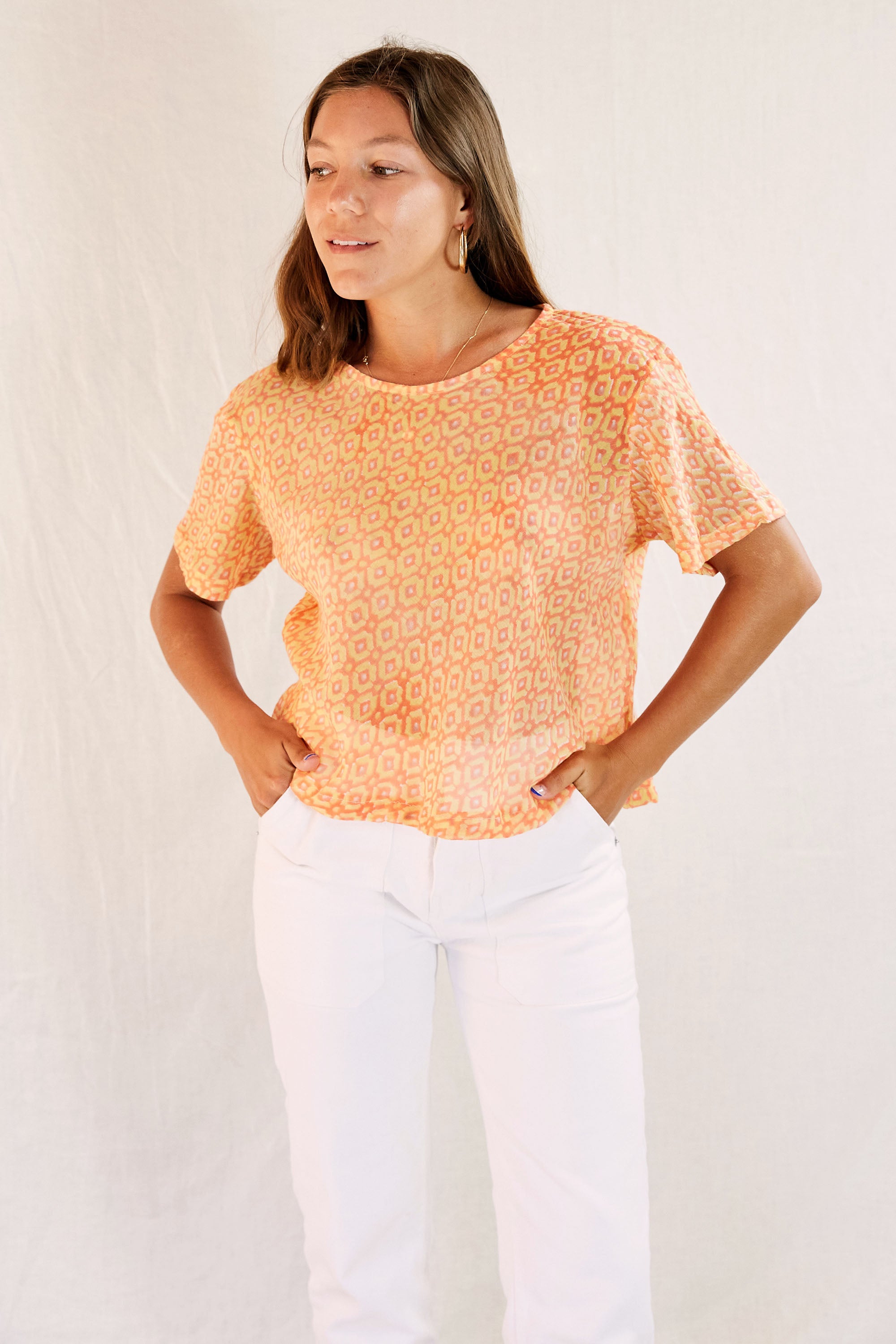 Model wearing the Sophie Top with white pants against a cream backdrop