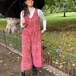 Woman wearing the Estella Corduroy Jumpsuit, while holding a black umbrella outside in the park