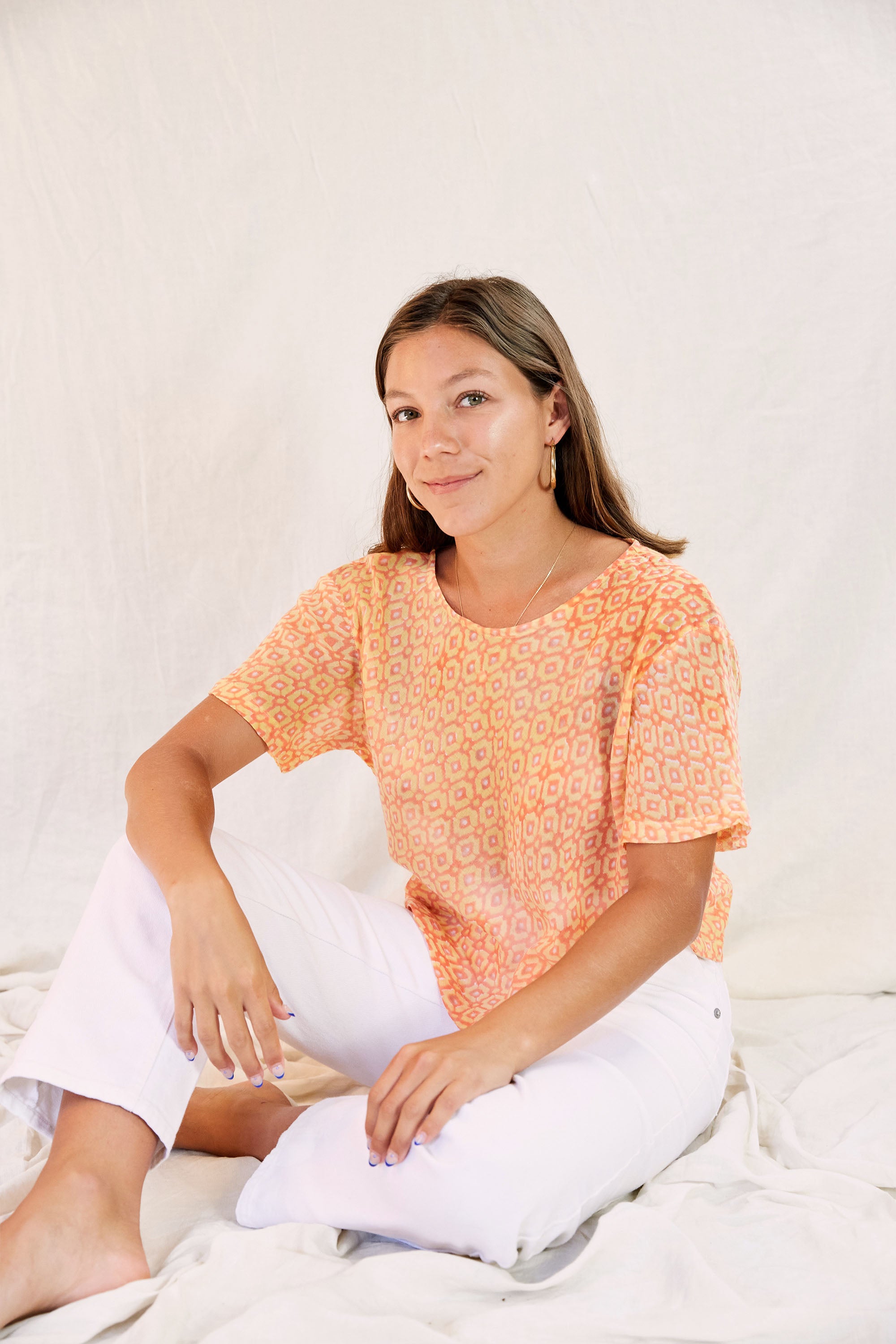 Model wearing the Sophie Top with white pants against a cream backdrop