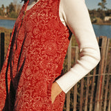 Model wearing the Estella Jumpsuit outside near water over a white long sleeve, close up of print on the side