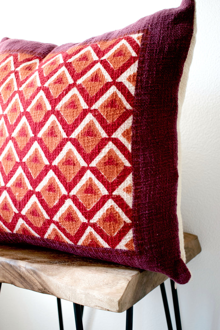 Pitaya block print pillow on a stool against white, angled