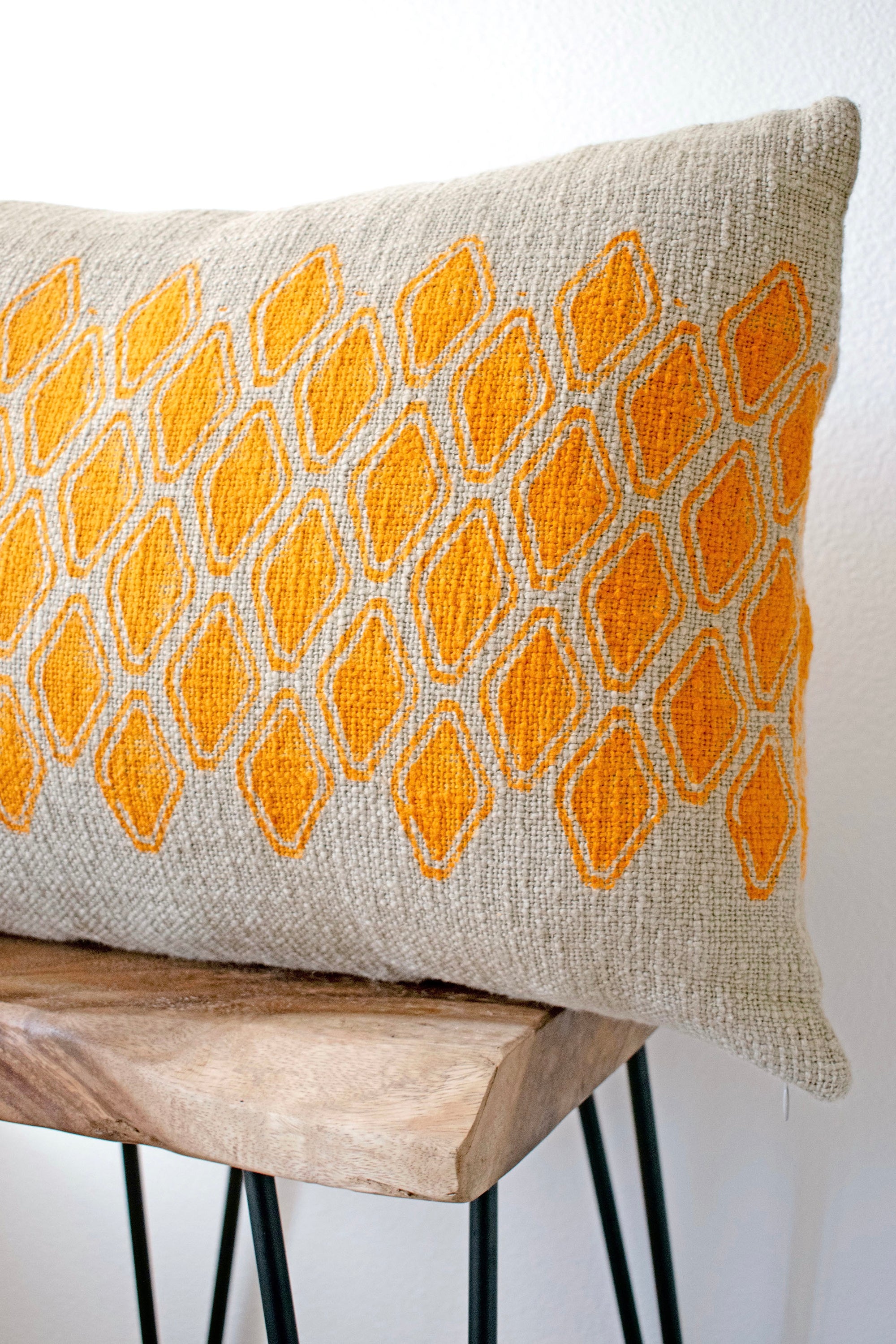 Sol Block Print Pillow on a stool against white, angled