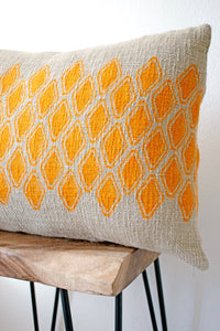 Sol Block Print Pillow on a stool against white, angled