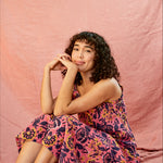 Model wearing the Kate strap dress against a blush background, model is sitting down