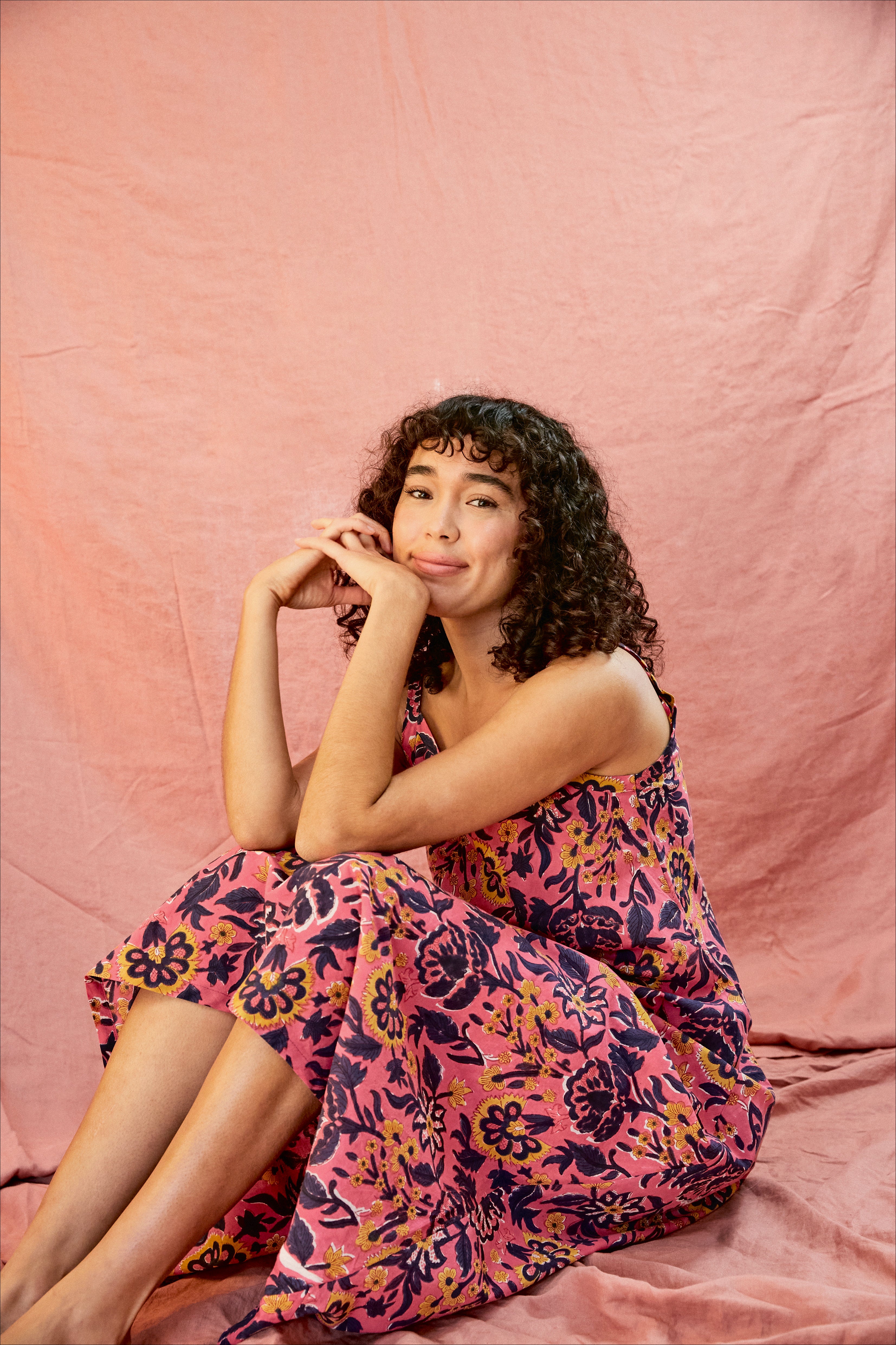 Model wearing the Kate strap dress against a blush background, model is sitting down