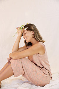 Model wearing the Alba set, against a cream color background, model is sitting down holding a flower