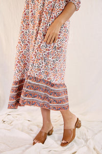 Close up of model wearing the Mia dress against a cream backdrop; focus on hem of dress