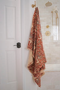 Rouge bath towel hanging on a hook in a bathroom