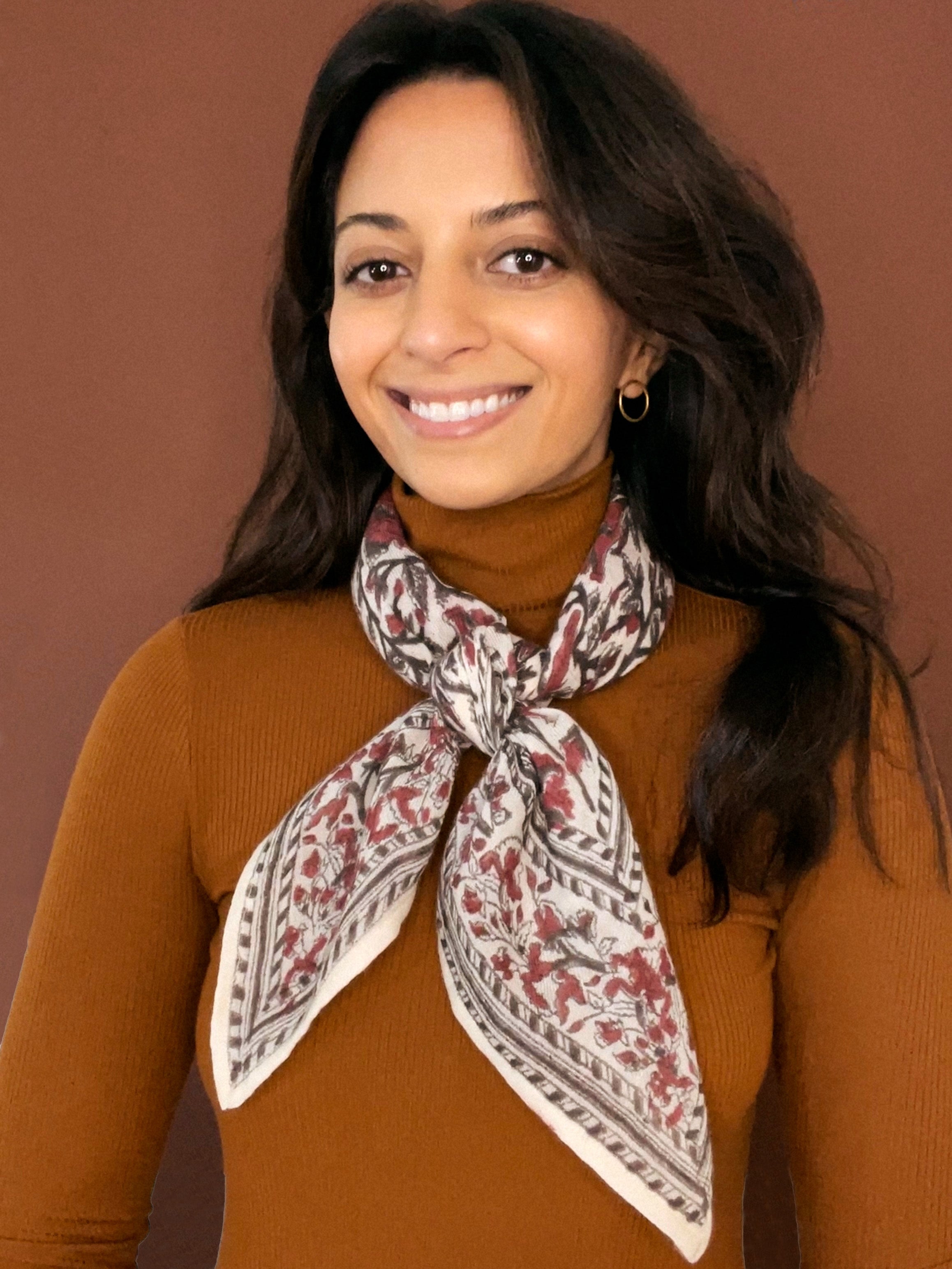 Model wearing the block printed Lana bandana tied around the neck against a brown background