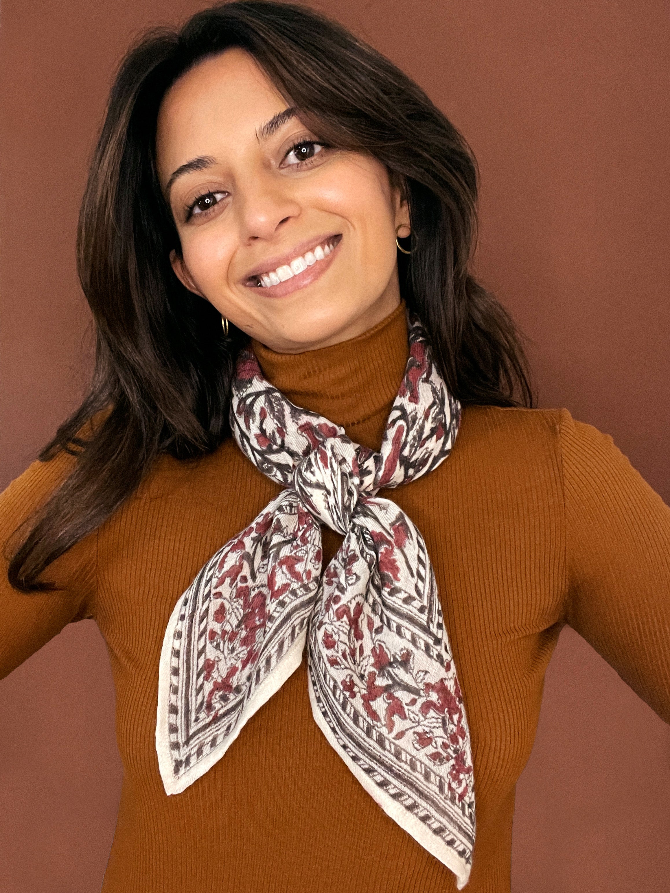 Model wearing the block printed Lana bandana tied around the neck against a brown background