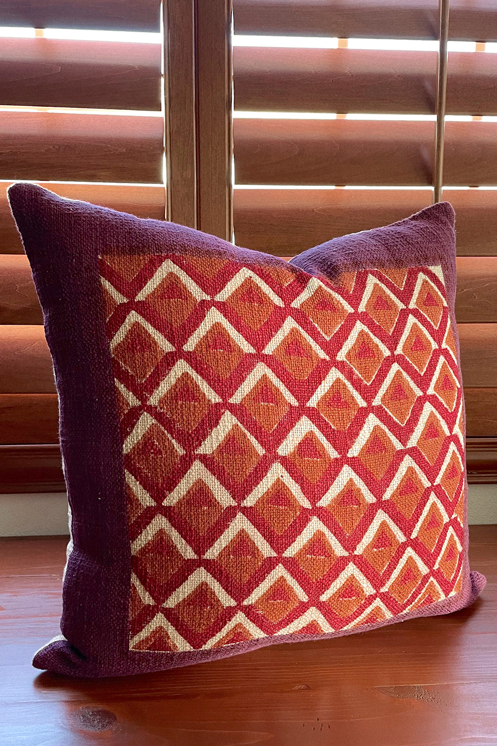 Pitaya block print pillow on a wooden desk, angled
